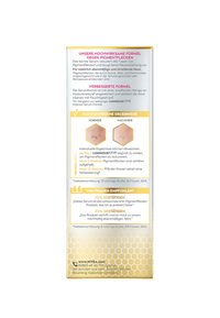 Product box for a serum, featuring a golden honeycomb pattern. Text in German highlights effectiveness against pigmentation, before-and-after results, and user recommendations.