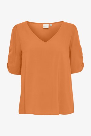 Oranžs V veida bluze ar īsām, savilktām piedurknēm un brīvu piegriezumu, attēlots uz baltā fona.