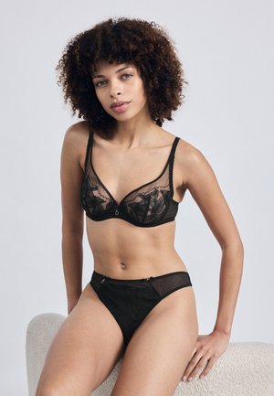 Svart spetslingerie-set bestående av en bh med genomskinliga kupor och justerbara band, matchat med trosor. Fina blommönster och små detaljer.