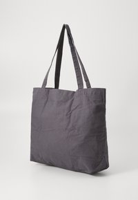 Borsa tote in tessuto grigia con due manici lunghi, caratterizzata da un design semplice e una superficie texture, adatta per l'uso quotidiano o per lo shopping.