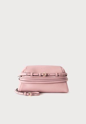 Sac à main en cuir rose doux avec des fines bretelles réglables et de petites boucles dorées sur un fond clair uni.