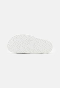 Suola di sandaletti bianco con motivo a zigzag, sei gommini circolari e logo "Levi's" impresso al centro.