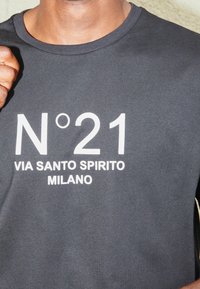 Czarna bawełniana koszulka z krótkim rękawem, z wyraźnym białym napisem "N°21 VIA SANTO SPIRITO MILANO". Okrągły dekolt.