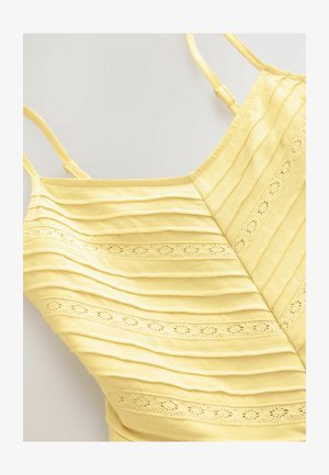 Żółta bezrękawnikowa bluzka z poziomą teksturą ryżu i ozdobnym wykończeniem z oczkami. Wykonana z miękkiego materiału, z regulowanymi ramiączkami.