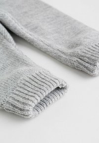Gray knitted cuffs of a garment with ribbed edges, displaying a soft texture and a smooth finish. The fabric appears lightweight and flexible.