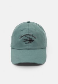 Világoszöld pamut sapka, fekete hímzett "Homeward brand" felirattal és egy fecske mintával az elején. Ívelt karima, állítható hátsó pánt.