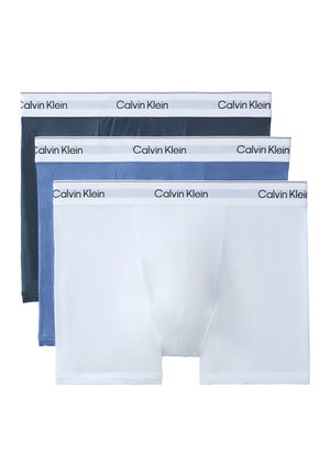 Tres bóxers para hombre de Calvin Klein en blanco, azul claro y azul oscuro con cinturas blancas que llevan el nombre de la marca.