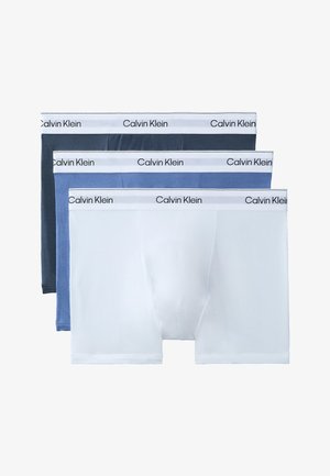 Drie Calvin Klein herenboxers in wit, lichtblauw en donkerblauw met witte taillebanden waarop de merknaam staat.