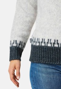 Neulepaita, jossa on vaalea harmaa vartalo, tummanharmaa ribbineulehelma ja mustavalkoinen kuviollinen kapea osa alareunassa. Sisältää sivulapun.