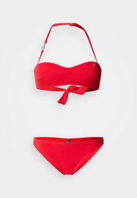 Σετ κόκκινου μπικίνι με τοπ χωρίς τιράντες με λεπτομέρεια κόμπου και ρυθμιζόμενες τιράντες, συνδυασμένο με αντίστοιχα σλιπ χαμηλής μέσης. Λείο υφής.