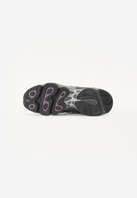 Suola di sneaker nera e grigia con accenti rosa prominenti, gomma testurizzata e battistrada con motivo per una migliore aderenza. Logo presente sul lato.