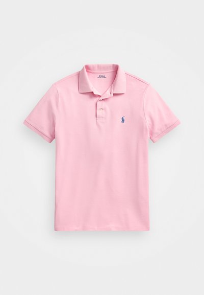 Roza polo majica iz bombažnega materiala. Ima klasičen ovratnik, kratke rokave in majhno modro logo na levem prsnem delu. Preprost dizajn.
