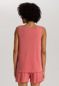 Top sin mangas de color rosa con un escote redondeado, combinado con unos pantalones cortos con volantes a juego. Hecho de una tela suave, con un corte relajado.