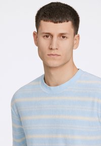 Ljusblå långärmad tröja med horisontella beiga ränder, med rund halsringning och mjukt, texturerat tyg.