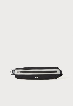 Nike crna torbica za struk, sa reflektirajućom srebrnom prugom, zatvaranjem na zip, mekim materijalom i akcentom s logotipom. Kompaktni pravokutni oblik.