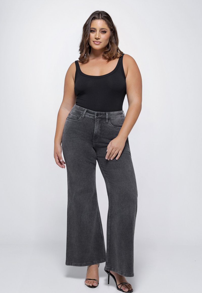 Zwarte bodysuit gecombineerd met hooggeknipte, wijdvallende grijze jeans. Zachte denim textuur, klassieke vijf-pocket ontwerp en subtiele vervaging.