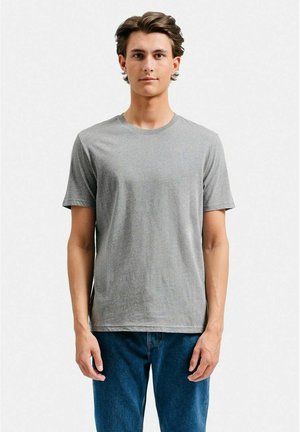 Grå bomulds t-shirt med korte ærmer og rund halsudskæring, der har en glat tekstur og en klassisk pasform. Bæres med blå jeans.