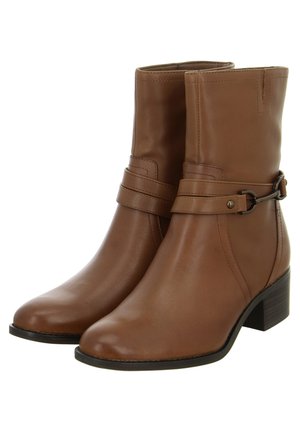 Braune Leder-Stiefeletten mit abgerundetem Zeh, einem niedrigen gestapelten Absatz und einem dekorativen Riemen mit metallischem Akzent um den Knöchel.
