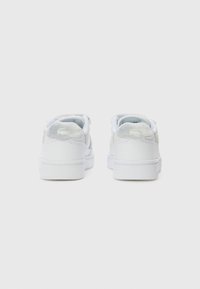 Baskets blanches avec une tige en cuir lisse, des accents texturés, un col rembourré et une semelle en caoutchouc légère. Détail de logo discret au niveau du talon.