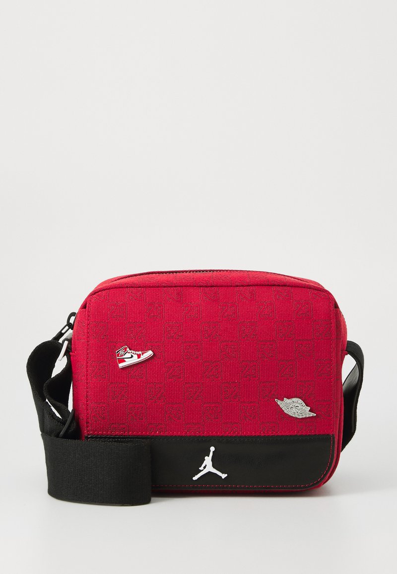 Borsa a tracolla rossa in tessuto con accenti neri, caratterizzata da motivi in rilievo, un logo Jordan e piccoli ornamenti metallici a forma di scarpa e ali.