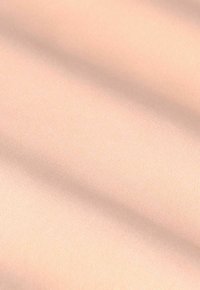 Zacht, lichtroze stof met zachte plooien die diagonale schaduwen en highlights creëren.