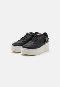 Czarne skórzane sneakersy z perforowanym czubkiem, grubą białą gumową podeszwą i małym detalem w postaci łańcuszka po boku. Sznurowany fason z akcentami logo.