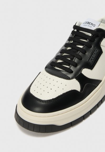 Sort-hvid læder sneakers med perforeret tå, polstret krave og sorte snørebånd. Har en struktureret sort panel og en chunky hvid sål.