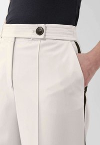 Witte op maat gemaakte broek met een gladde textuur, plooien, een knoopsluiting op de tailleband en zijzakken met contrasterende donkere accenten.