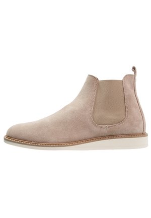 Beige Wildleder Chelsea-Boot mit elastischem seitlichem Einsatz, Zuglasche auf der Rückseite und hellem Sohlen, seitlich dargestellt.