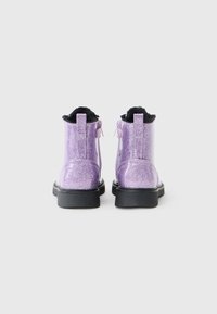 Bottines à paillettes violettes avec doublure en fourrure noire, semelle épaisse noire et fermeture éclair à l'arrière pour un enfilage facile.