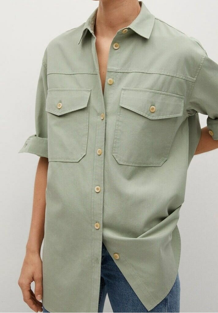 Chemise oversize vert clair avec deux poches poitrine et manches retroussées, ornée de boutons en bois et d'une texture lisse et subtile.
