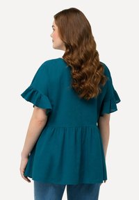 Tyrkysový peplum top s krátkými volánkovými rukávy, vyrobený z lehkého materiálu, s volným střihem a detailem staženého pasu.