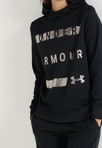 Felpa nera con cappuccio caratterizzata da testo e logo "UNDER ARMOUR" in argento. Tessuto morbido, vestibilità comoda e polsini e orlo a costine.
