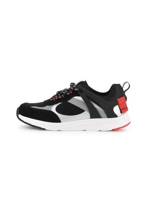 Basket de sport noire, grise et blanche avec des accents rouges, en mesh et en suède, avec une languette de talon brandée sur fond blanc.