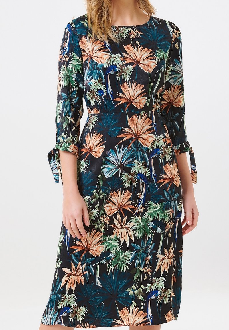 Blumenmuster-Kleid mit Dreiviertelärmeln, schwarzem Hintergrund, orangen, grünen und blauen Mustern, Bindebändern an den Ärmelenden, knielanger Schnitt.