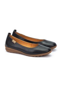 Ballerines en cuir noir avec un bout arrondi, design minimaliste, semelle en caoutchouc brun flexible et doublure intérieure beige.