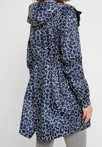 Navy raincoat featuring a white star pattern, adjustable hood, elastic waistband, and long sleeves with elastic cuffs.