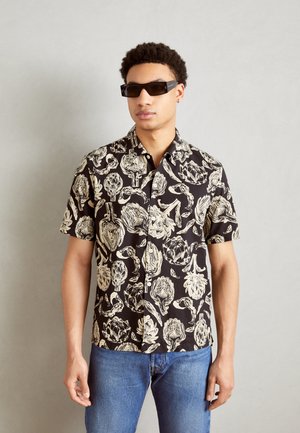 Short-sleeved black shirt featuring a white outline floral print, with a button-up design. Worn with sunglasses.