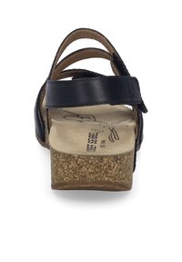 Zwarte leren sandaal met meerdere banden, een geweven kurken voetbed en een dikke zool. Beschikt over een lichte hak en een verstelbare gesp.