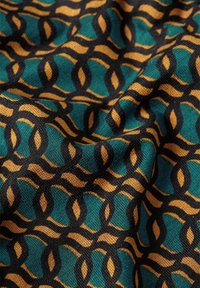 Textil mit einem geometrischen Muster in Türkis-, Schwarz- und Goldtönen. Das Design umfasst ineinandergreifende ovale Formen mit einer strukturierten Oberfläche.
