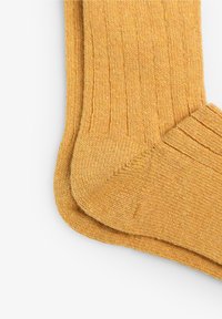 Calze gialle lavorate a maglia con un polsino a coste e un motivo diagonale, caratterizzate da una trama liscia e un design della punta senza cuciture.