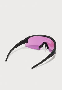 Czarne sportowe okulary przeciwsłoneczne z pojedynczą zakrzywioną różową soczewką i regulowanymi noskami na białym tle.