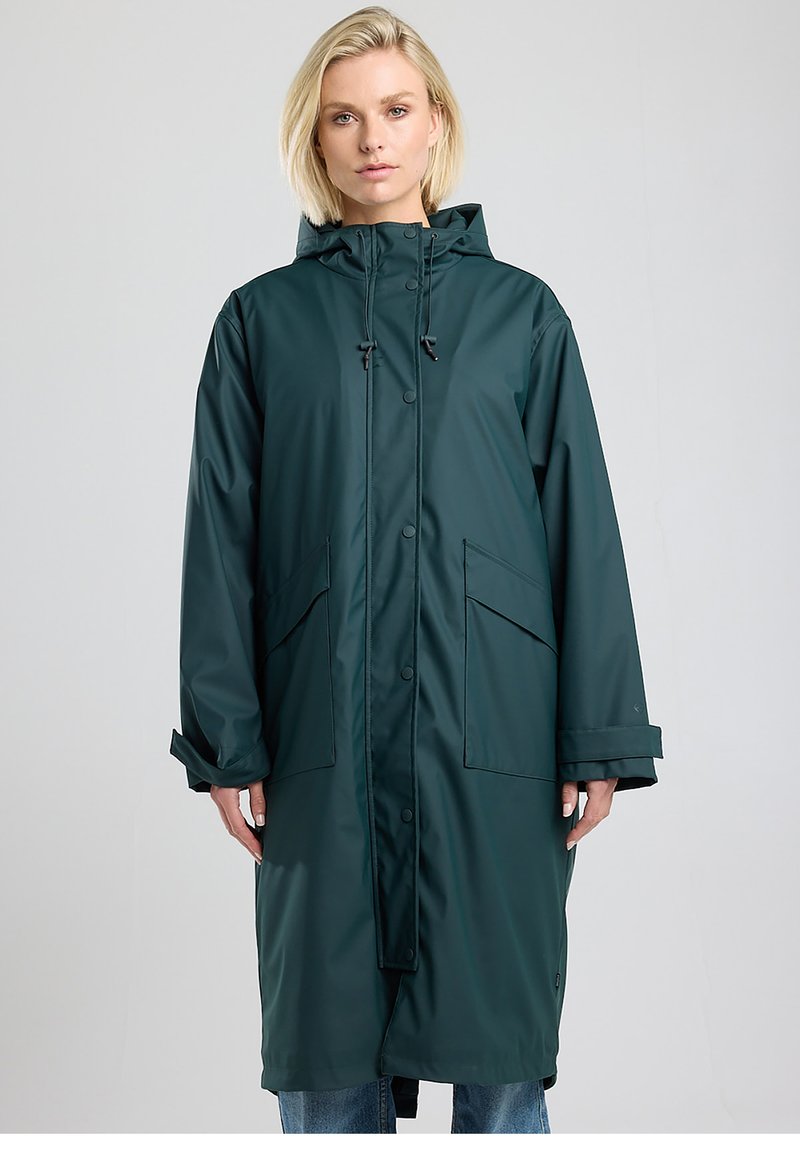 Long manteau imperméable vert foncé, doté d'une capuche avec cordon de serrage, de grandes poches avant et de fermetures à boutons. Texture lisse et brillante.