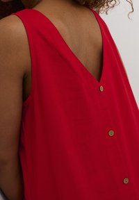 Rotes ärmelloses Oberteil mit V-Ausschnitt und fünf Knöpfen auf der Vorderseite. Hergestellt aus leichtem Stoff, mit einer glatten Textur und lockerem Schnitt.
