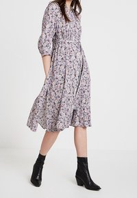 Blommönstrad klänning i lätt tyg, med puffärmar, en cinchad midja och en svävande kjol. Matchad med svarta ankellånga stövlar.