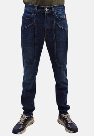 Jeans in denim blu scuro con design a gamba dritta, caratterizzati da ampie tasche frontali e dettagli di cucitura sottili. Indossati con sneaker grigie.