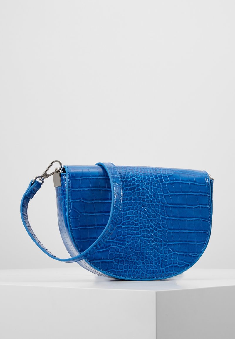 Borsa blu con stampa a coccodrillo, dalla forma curva, finitura lucida e tracolla regolabile. Dotata di una chiusura metallica e un design elegante.