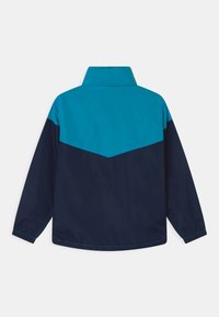 Färgsorterad jacka med en ljusblå överdel och en mörknavy underdel. Tillverkad av lätt material med ståkrage.