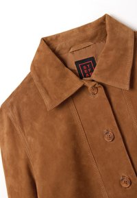Giacca in suede marrone con colletto a punta, due bottoni e una texture liscia. L'etichetta interna riporta "STEFAN."