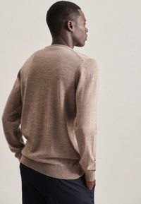 Beige Strickpullover mit langen Ärmeln, gerippten Bündchen und Saum, lässiger Schnitt und subtile Textur. Schlichtes Design, ohne sichtbare Muster.